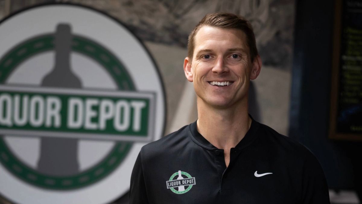 Trey Lawson stands inside Liquor Depot next to a whiskey barrel.