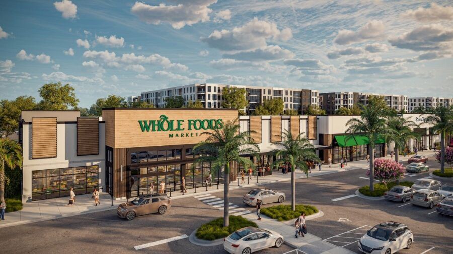Rendering of the Sarasota Square redevelopment featuring a new Whole Foods Market, surrounding storefronts and outdoor pedestrian areas, with multifamily residential buildings in the background.