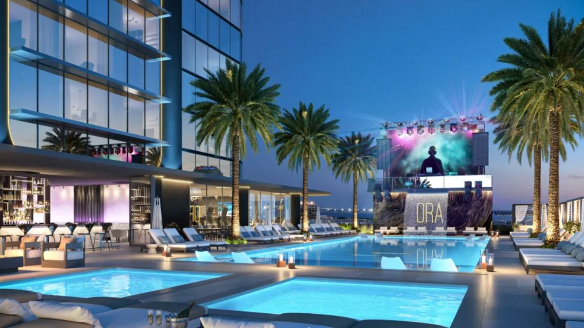 Rendering of Hotel ORA’s rooftop pool deck at sunset, featuring palm trees, lounge chairs, and an illuminated stage.