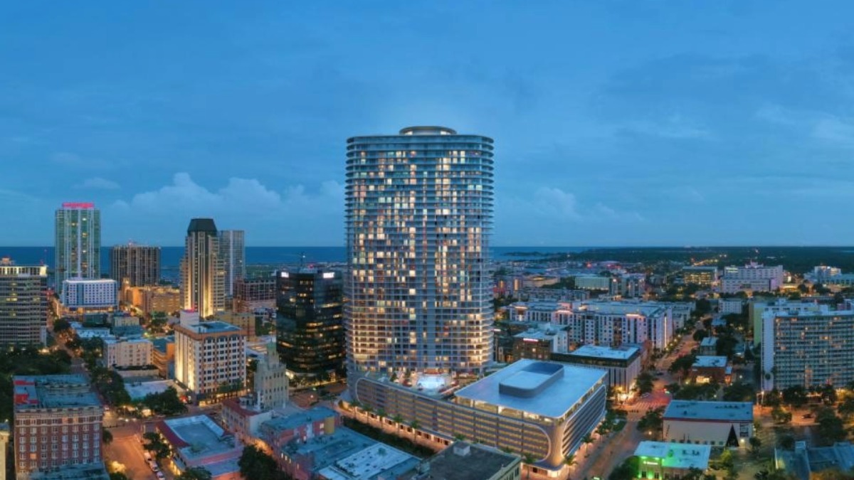 A nighttime aerial view of downtown St. Petersburg with the 400 Central tower lit up at the center of the skyline.