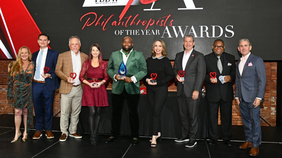 Group photo of all award recipients from the 2025 TBBW Philanthropists of the Year Awards standing on stage holding their trophies.