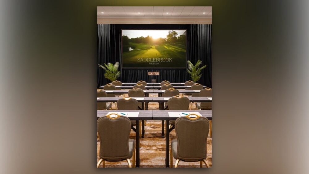 Classroom-style meeting room at Saddlebrook Resort with tables, chairs and a large presentation screen