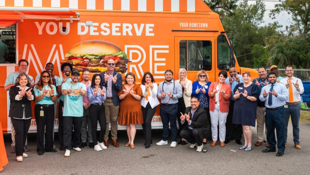 Whataburger corporate and Tampa Bay community members stand in front of the Whataburger food truck holding up “W” hand signs.