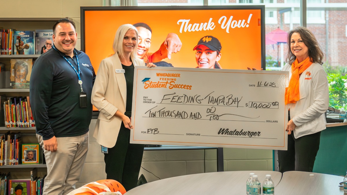 Whataburger leaders present a $10,000 donation check to Feeding Tampa Bay inside the Kenly Elementary media center.