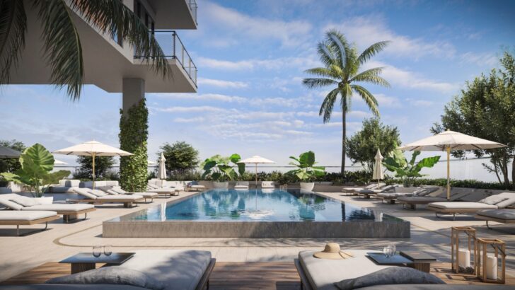 Pool deck at Gallery Haus with lounge chairs, palm trees and a raised swimming pool.