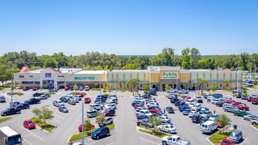 Aerial view of Grove Park Shopping Center in Lakeland featuring a rebuilt Publix, CVS and Dollar Tree with a full parking lot and surrounding greenery under a clear blue sky