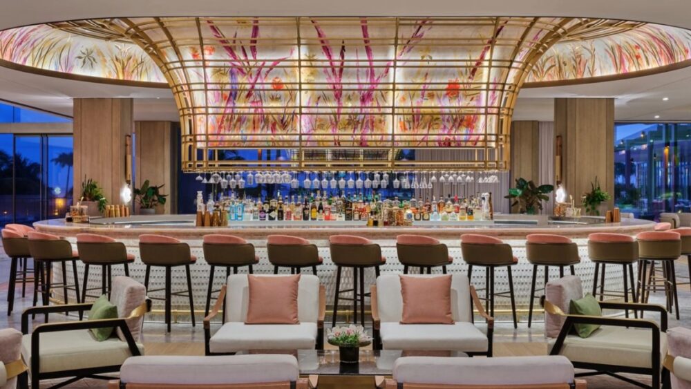 The St. Regis Longboat Key lobby bar with a sculptural illuminated canopy, pink seating, and a full cocktail display.