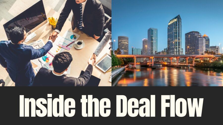Business leaders finalize a deal during a meeting alongside a view of Tampa’s downtown skyline.