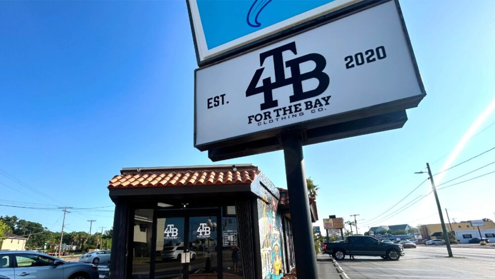 For the Bay Clothing Co. storefront on Henderson Boulevard with the 4TB sign visible in front of the building