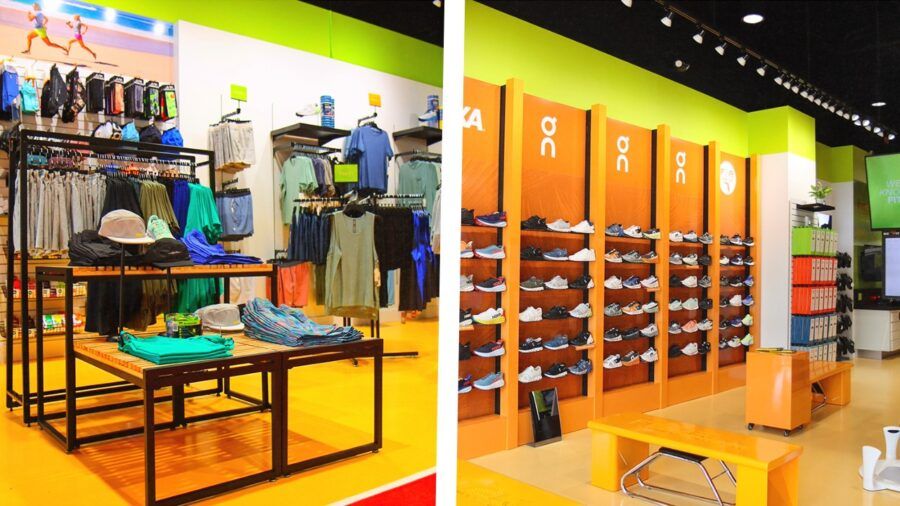 Interior views of the new Fit2Run pop-up at Water Street Tampa showing apparel displays, accessories and a wall of running shoes from brands like HOKA and On.