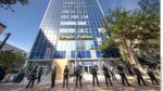 Tampa Police officers standing in a line in front of the Tampa Police Department headquarters, a tall blue-glass building in downtown Tampa.