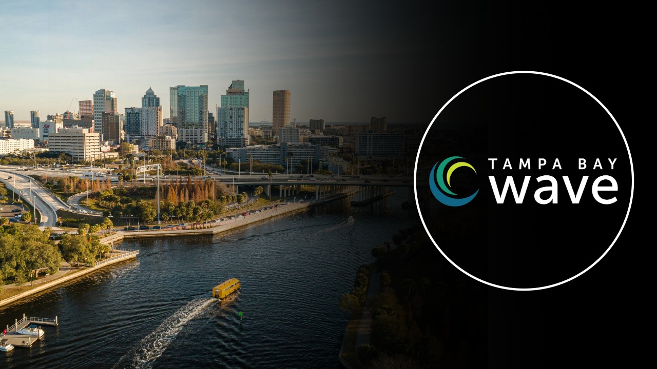 Aerial view of downtown Tampa along the Hillsborough River with the Tampa Bay Wave logo overlaid.