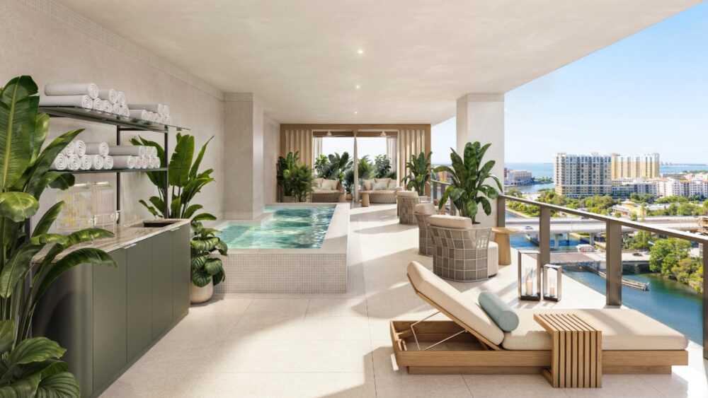 A spa deck at Pendry Tampa featuring loungers, greenery, and a water view