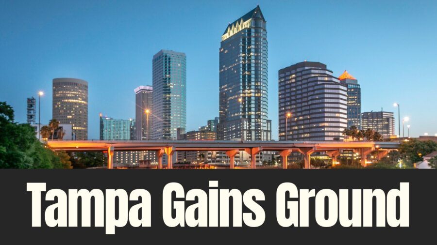 Downtown Tampa skyline at dusk with illuminated office towers and highway overpass as the city gains national recognition for corporate headquarters growth