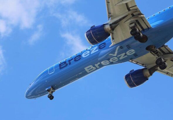 Breeze Airways Airbus A220-300 aircraft in flight against a clear blue sky