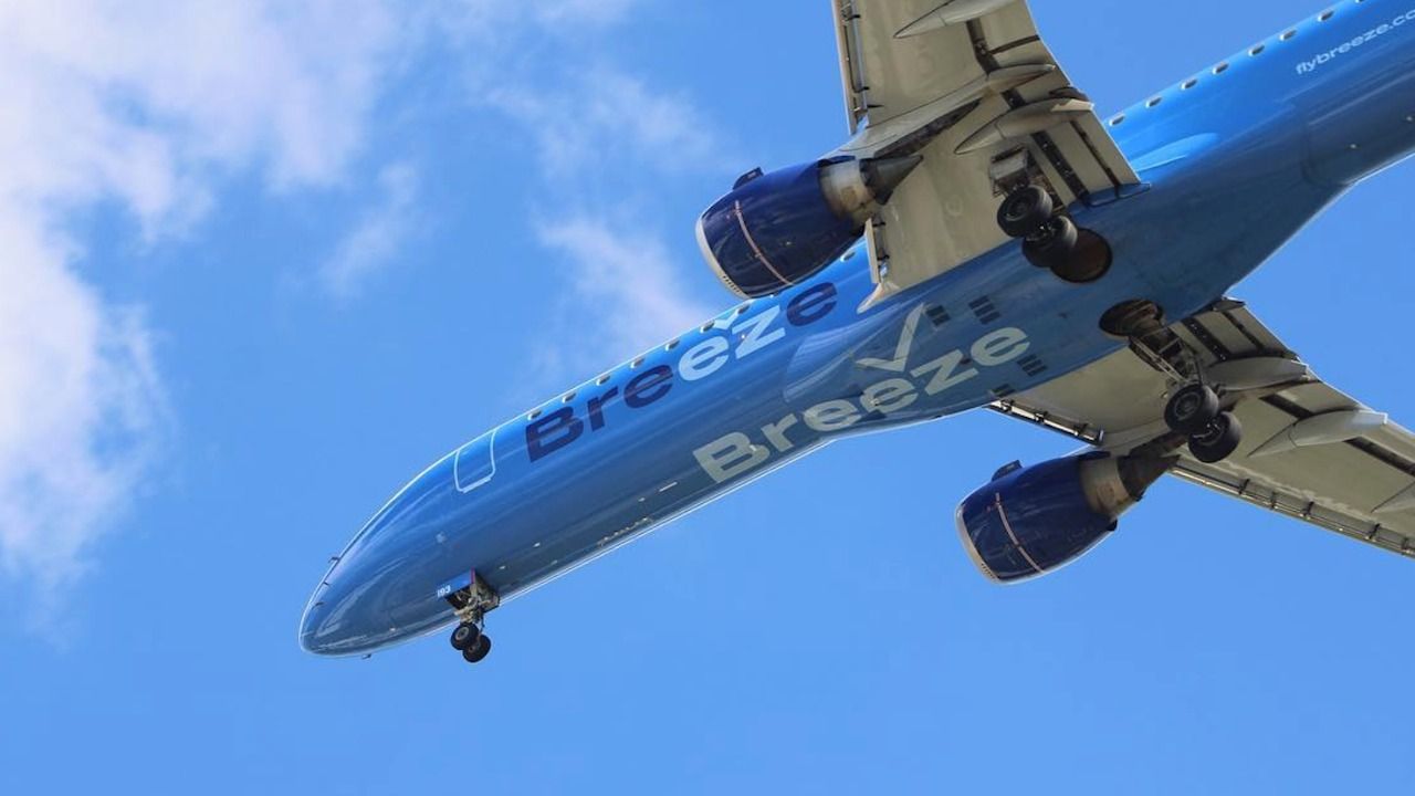 Breeze Airways Airbus A220-300 aircraft in flight against a clear blue sky