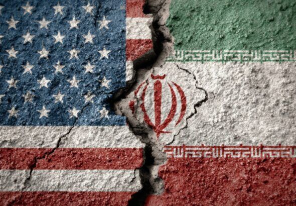 Cracked concrete wall painted with the U.S. and Iranian flags facing each other