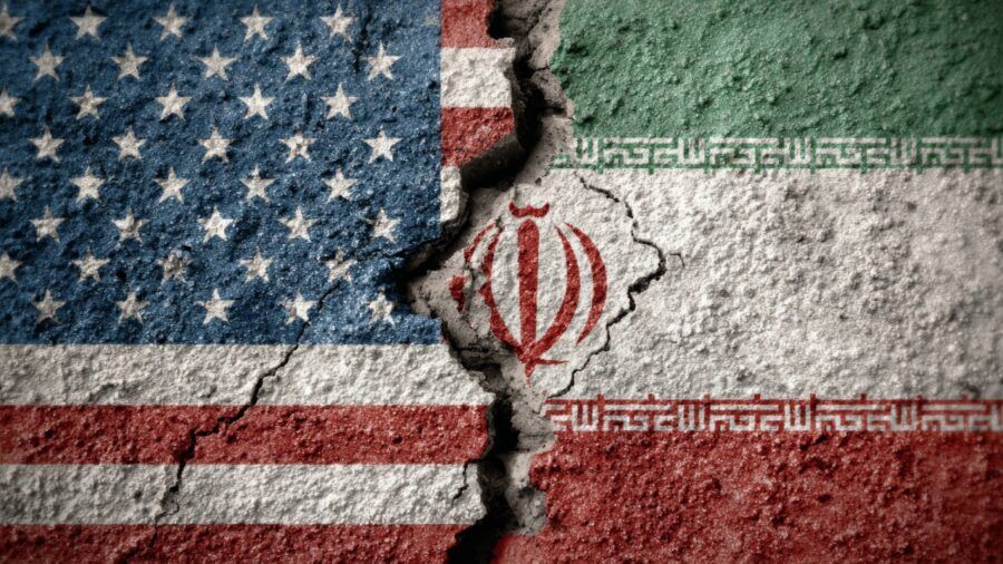 Cracked concrete wall painted with the U.S. and Iranian flags facing each other