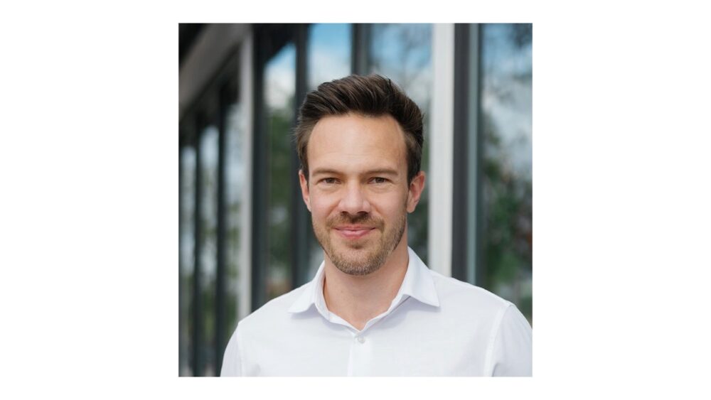 Healthcare technology founder standing outside an office building, wearing a white shirt.