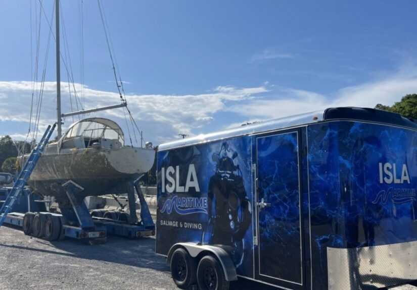Isla Maritime trailer and salvage equipment parked beside a sailboat on a trailer in Port Richey.
