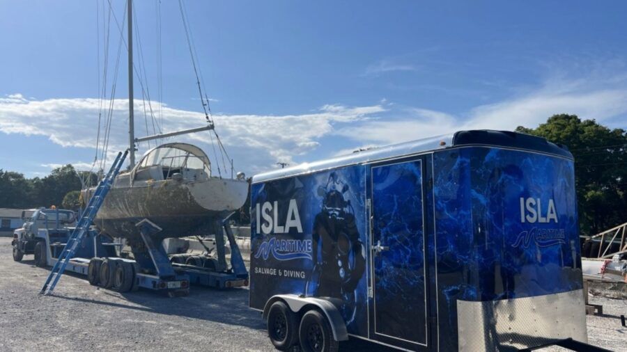 Isla Maritime trailer and salvage equipment parked beside a sailboat on a trailer in Port Richey.