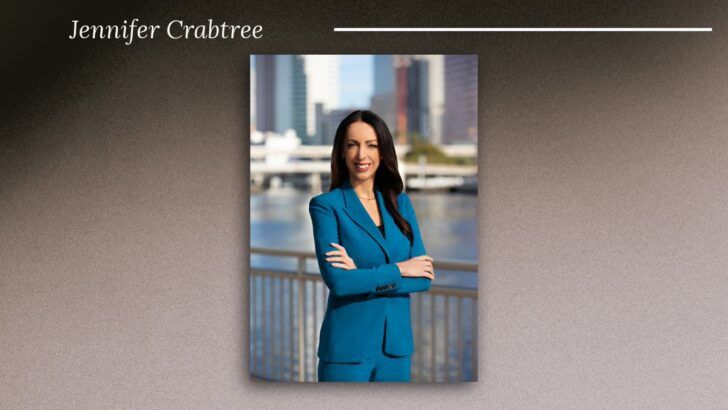 Portrait of Jennifer Crabtree, senior vice president at Tampa General Hospital, standing along the Tampa Riverwalk with the downtown Tampa skyline in the background.
