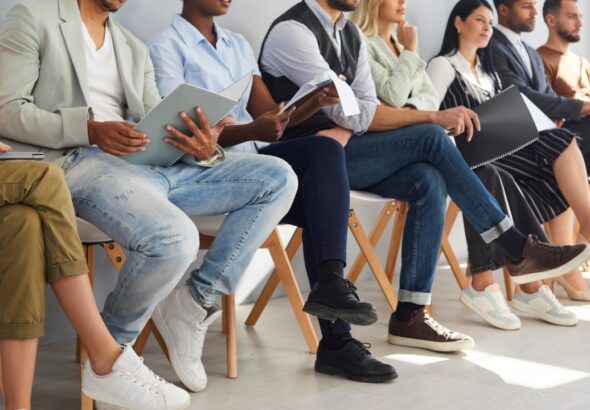Job candidates seated in a row holding resumes during an employment interview process