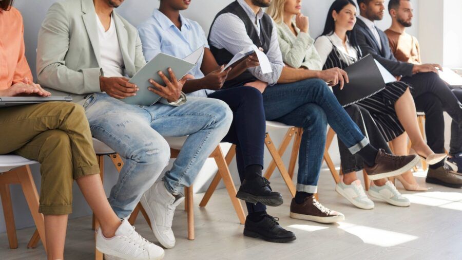 Job candidates seated in a row holding resumes during an employment interview process