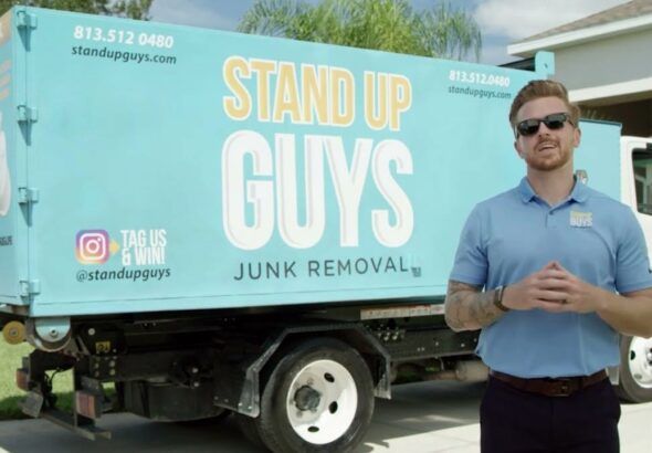 Casey Walsh stands in front of a Stand Up Guys Junk Removal truck in Tampa.