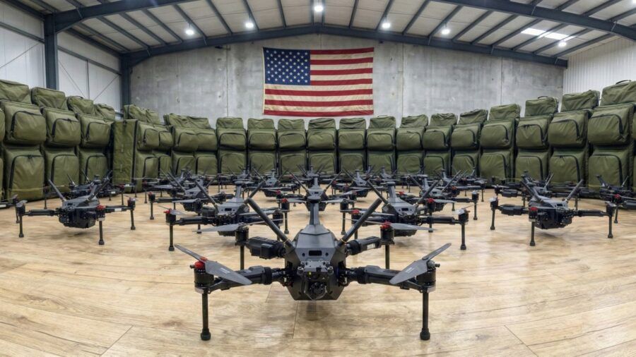 Rows of XTEND drone systems arranged inside a warehouse with a large American flag displayed on the back wall.