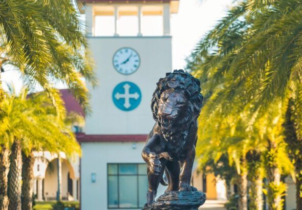 Lion statue on the Saint Leo University campus with the university’s clock tower in the background