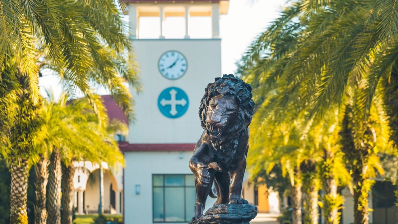 Lion statue on the Saint Leo University campus with the university’s clock tower in the background