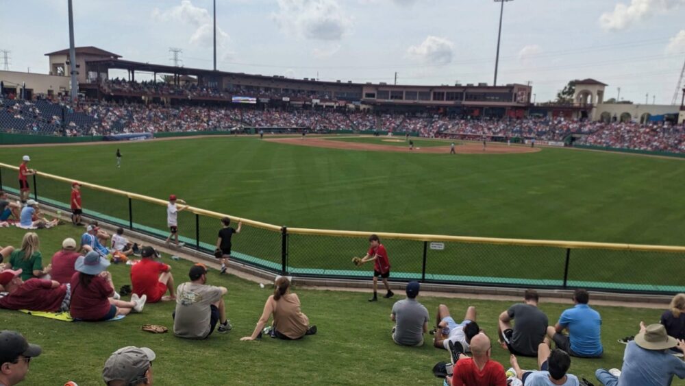 Fans sit on the grassy outfield berm at BayCare Ballpark during a spring training game in Clearwater.