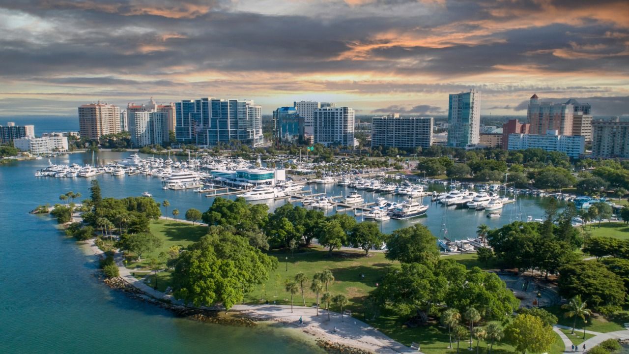 Aerial view of Sarasota waterfront with marina, park and downtown skyline at sunset