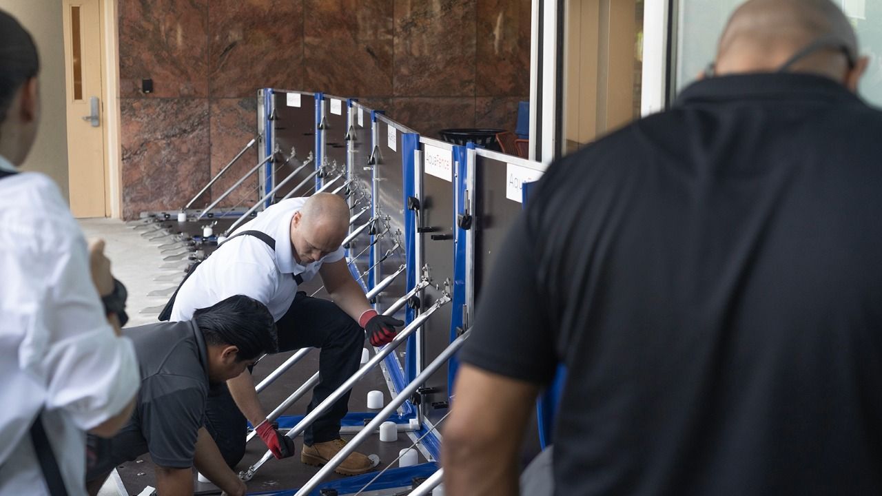 Workers install AquaFence flood barrier system at Naples hospital campus entrance