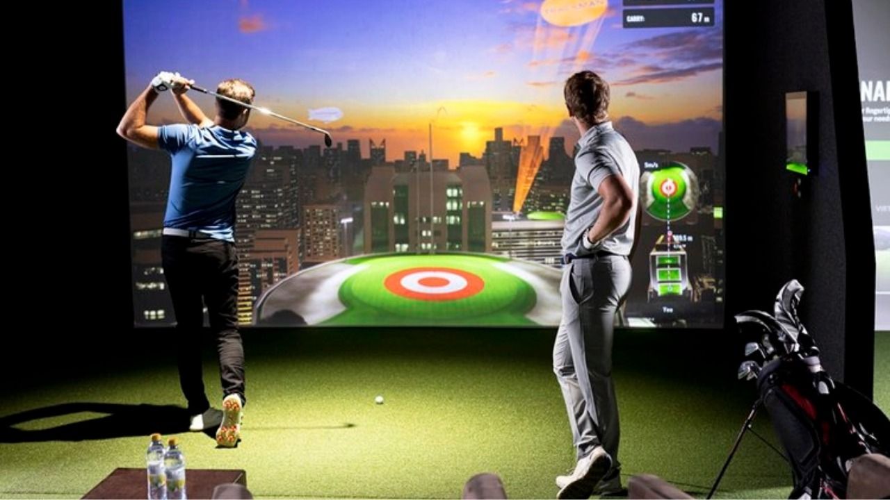 Indoor golf simulator with players hitting shots toward a digital course display