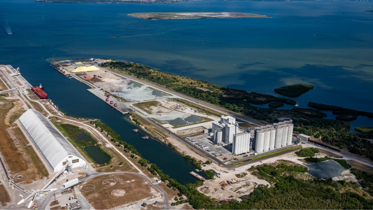 Aerial view of Port Redwing bulk terminal in Tampa Bay with storage piles, silos and docked cargo vessel