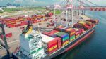 Container ship at Port Tampa Bay with stacked cargo containers and cranes loading freight along the waterfront