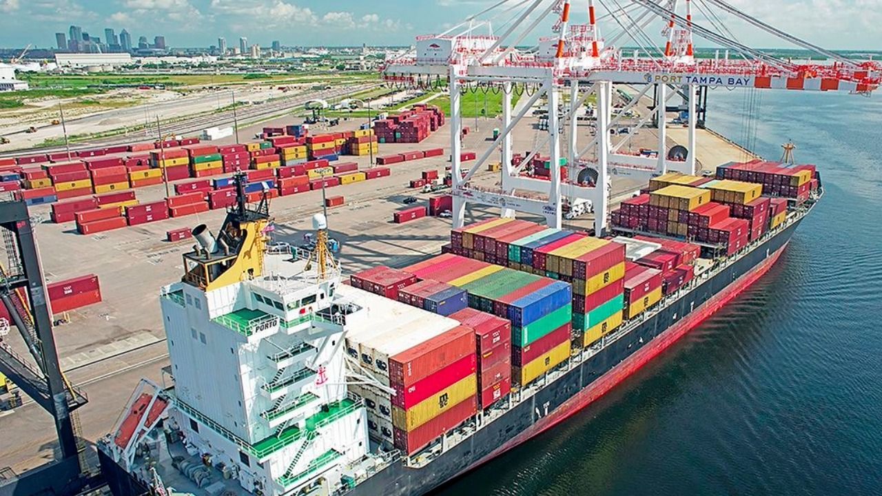 Container ship at Port Tampa Bay with stacked cargo containers and cranes loading freight along the waterfront