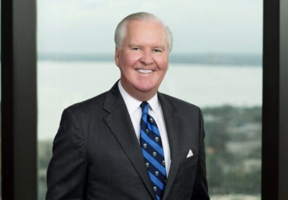 Bob Buckhorn, former Tampa mayor, in a suit and tie with waterfront backdrop