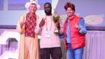 Nick Friedman, Modi Oyewole and Omar Soliman hold a trophy onstage at a College HUNKS event