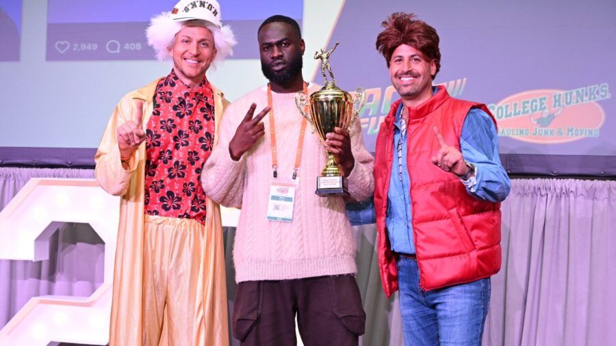 Nick Friedman, Modi Oyewole and Omar Soliman hold a trophy onstage at a College HUNKS event