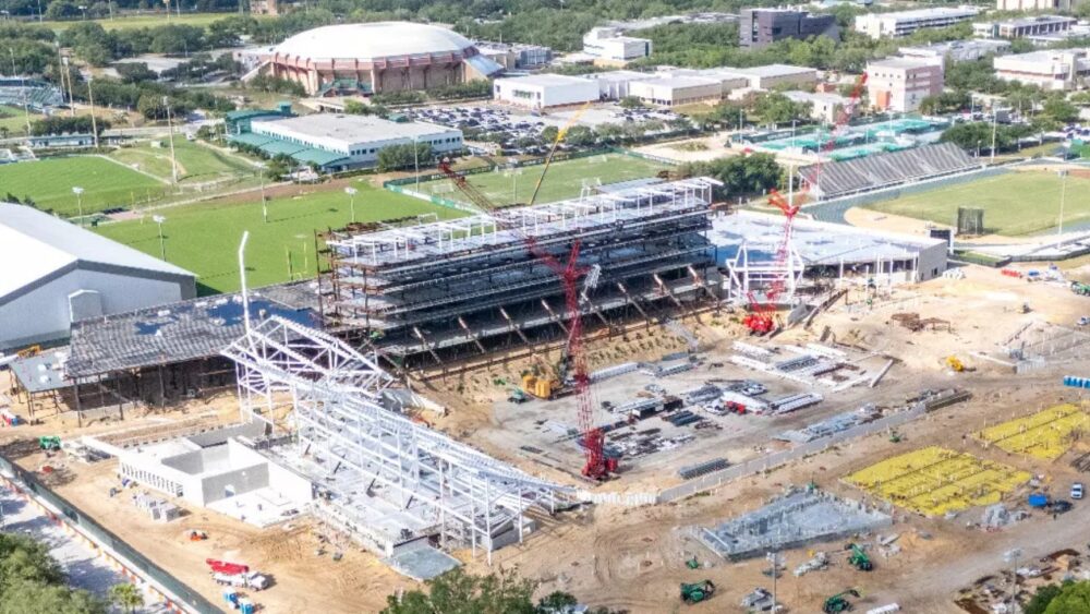 Aerial view of USF’s on-campus football stadium construction site with cranes and steel framework rising in Tampa.