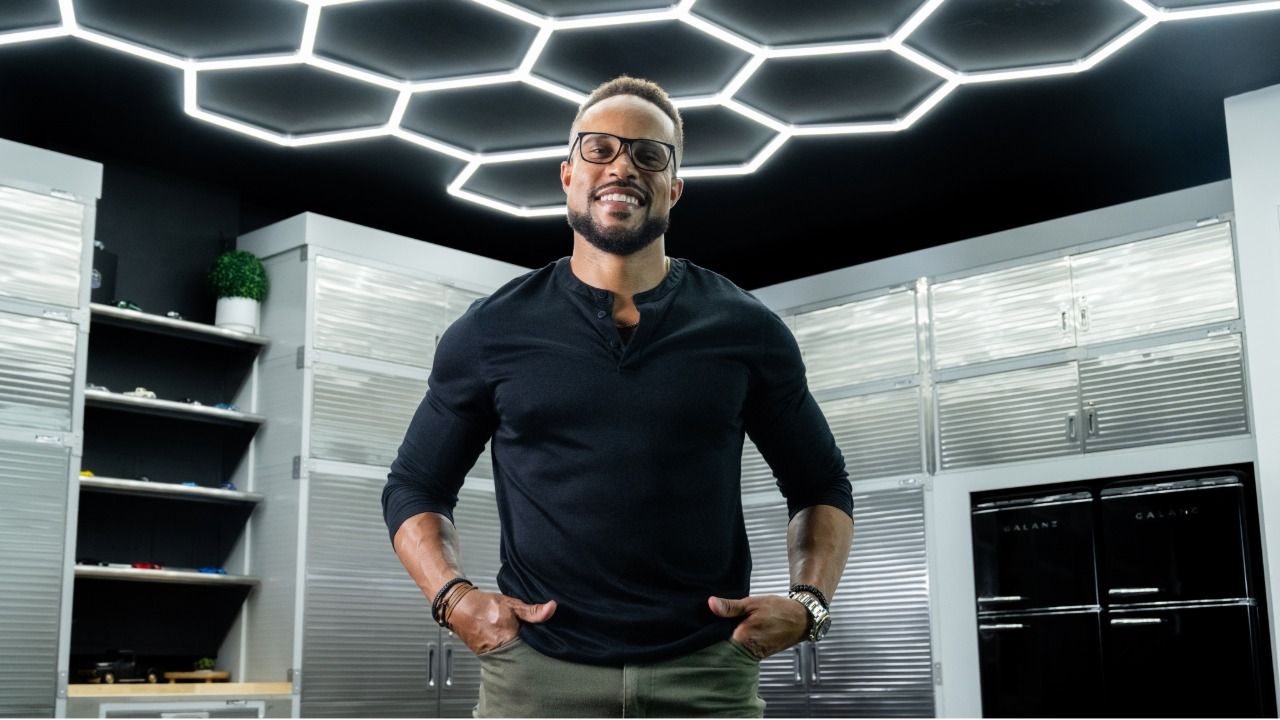 Allen Greene II stands inside a garage workspace beneath geometric ceiling lights during a portrait session.