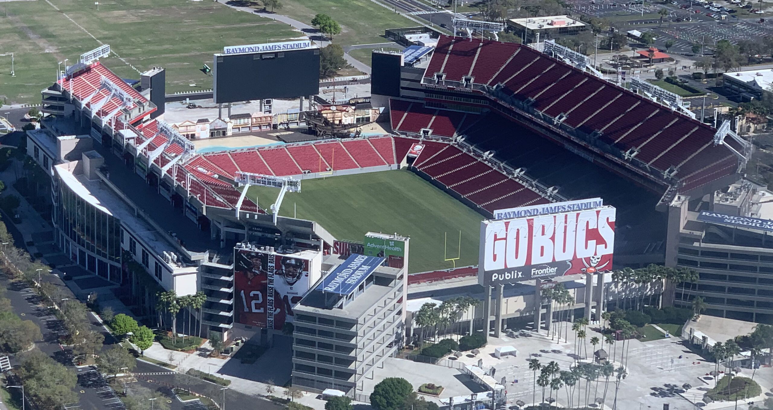 Aerial view of Raymond James Stadium in Tampa with its red seats, football field and pirate ship visible.