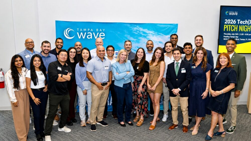 Group photo of attendees at Tampa Bay Wave's 2026 Tech|X Pitch Night, gathered in front of a Tampa Bay Wave banner at the organization's Tampa headquarters.