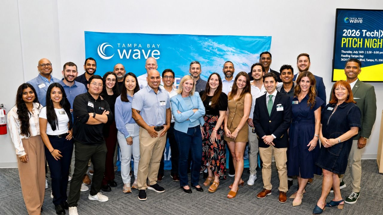 Group photo of attendees at Tampa Bay Wave's 2026 Tech|X Pitch Night, gathered in front of a Tampa Bay Wave banner at the organization's Tampa headquarters.