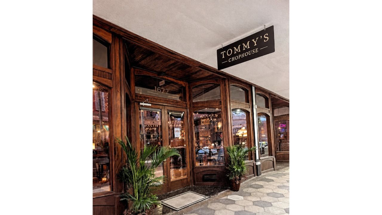 Wood-framed entrance to Tommy’s Chophouse in Ybor City, with potted palms flanking the doorway.