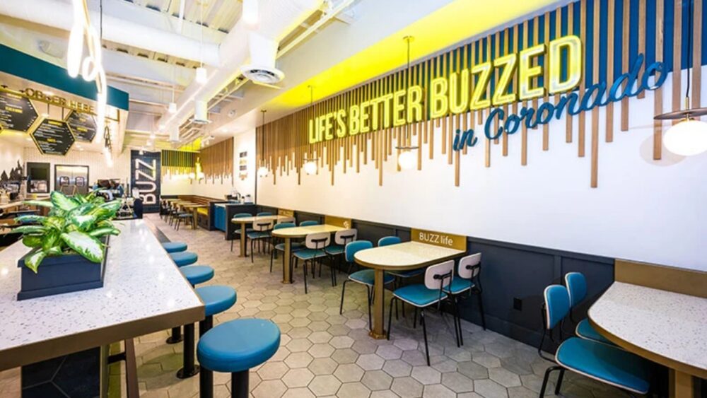 Interior of a Better Buzz Coffee café with tables, counter seating and illuminated wall signage
