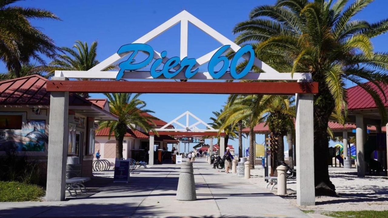Entrance to Pier 60 on Clearwater Beach, framed by palm trees and the blue Pier 60 sign.
